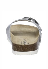 Stříbrné skluzavky se strukturovaným svrškem, korkovou stélkou a bílou gumovou podrážkou. Obsahuje jeden nastavitelný popruh s přezkou.