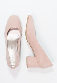 Scarpe con tacco blocco in suede rosa, con punta arrotondata e soletta imbottita. La suola è di un colore beige chiaro, caratterizzata da una texture liscia.