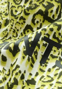 Tessuto leopardato giallo e verde con una texture liscia, caratterizzato da audace scrittura nera integrata nel design.