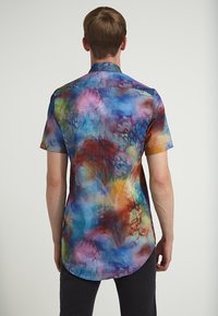 Košile s krátkým rukávem na knoflíky s vícebarevným batikovým vzorem v modrých, fialových a žlutých tónech. Hladká látka s zaobleným lemem.