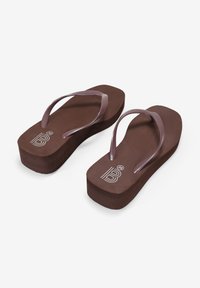 Chanclas marrones con una suela gruesa, adornadas con tiras moradas. La plantilla es lisa y tiene un logo en el lateral. Los detalles incluyen bordes redondeados.