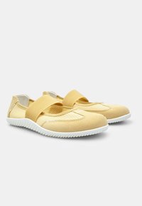 Scarpe slip-on a rete gialla con suola in gomma bianca, dotate di una ampia fascia elastica a metà piede e dettagli testurizzati sulla parte superiore.