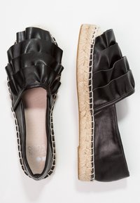 Espadrillas nere slip-on con tomaia sintetica a strati e a volants, suola intermedia in juta e cuciture a contrasto. Design con punta chiusa.