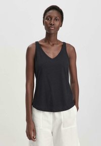 Top negro sin mangas con diseño de escote en V, hecho de una tela suave, con un corte holgado y un dobladillo ligeramente curvado.