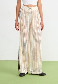 Kreeminväriset laiad püksid, mis on valmistatud transparentsest, tekstuuriga kangast, millel on vöötkrae muster, kontrasteeriva musta külgtriibuga ja elastse vööga.