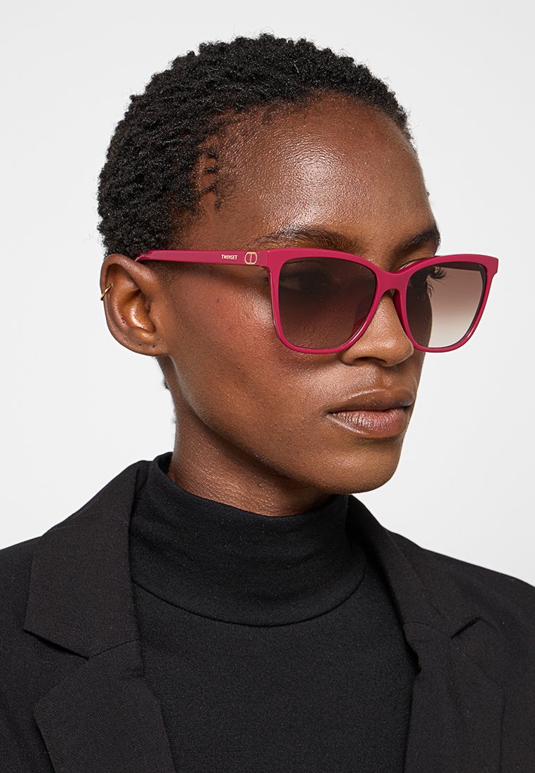 Occhiali da sole cat-eye fucsia con lenti sfumate, dotati di una montatura spessa e liscia e di un minimo dettaglio del logo su un lato.