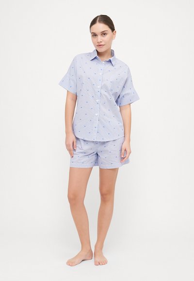 Camisa de botones de manga corta a rayas azules y blancas con patrones de corazones, combinada con pantalones cortos a juego, hecha de tela ligera.