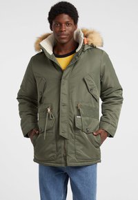 Khakigrüner Parka mit Kapuze aus Kunstfell, zwei aufgesetzten Fronttaschen, verstellbaren Kordelzügen in der Taille und einem Reißverschluss.