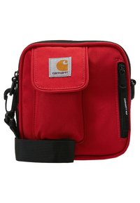 Red rectangular canvas bag with a front flap pocket, black zippers, and adjustable strap. Features a Carhartt logo on front.