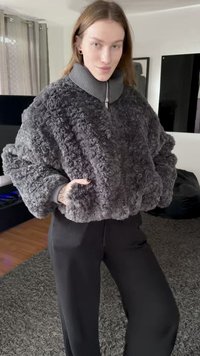 Gray fluffy fur jacket with a high-neck, zippered collar. Loose fit, volumetric sleeves, paired with black trousers. Soft texture, cozy appearance.