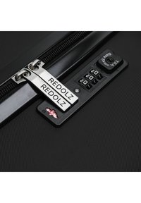 Maleta rígida negra con cremallera de doble tirador plateado etiquetada "REDOLZ". Cuenta con un candado de combinación y una superficie texturizada.