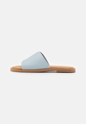 Light blue suede slide sandal with a wide strap and smooth tan leather insole. Features minimal design and flat natural rubber outsole.