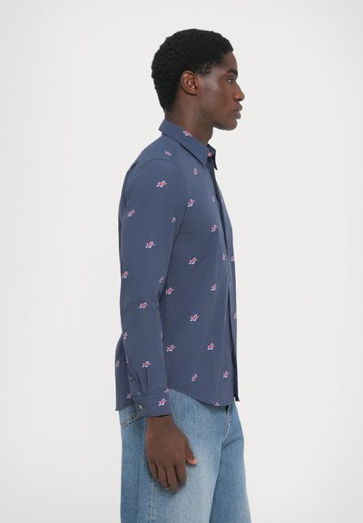 Marineblå knappskjorte med rosa blomstermønster, lange ermer, slim fit og en svakt buet nederkant. Stoffet ser glatt ut med en lett tekstur.
