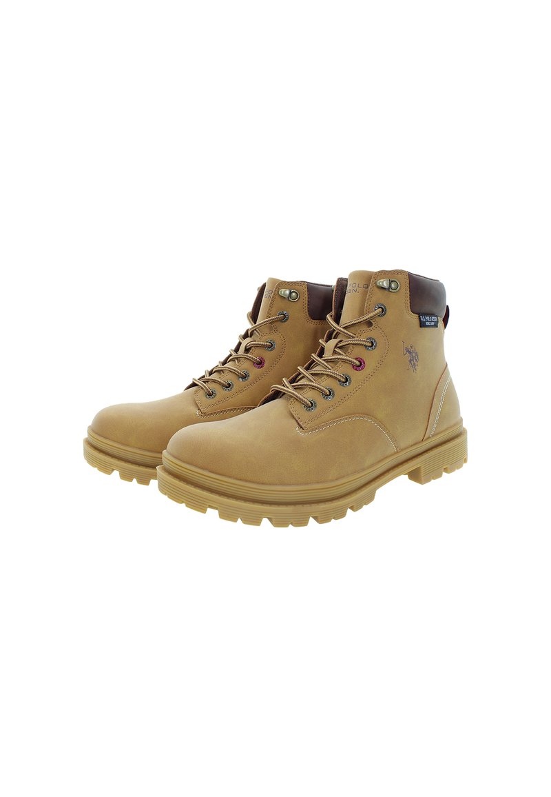 Bottes chelsea à lacets en cuir tan avec des semelles en caoutchouc épaisses et un logo noir sur les côtés, présentées sur un fond blanc.
