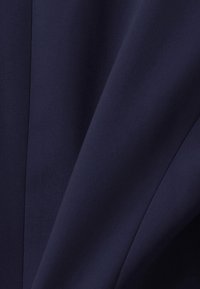 Marinblått tyg med en slät textur, som har en subtil lyster och fall, och visar vikta lager och sömdetaljer.