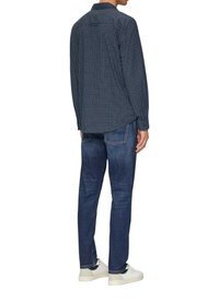 Marineblauw geblokt overhemd met lange mouwen, button-down kraag en afgeronde zoom, gecombineerd met donkerblauwe jeans en witte sneakers.