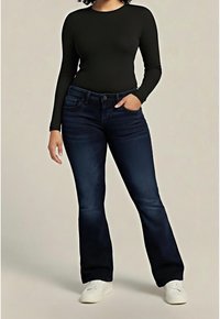 Haut noir à manches longues associé à un jean évasé bleu foncé. Le jean est équipé d'une braguette avec bouton et fermeture éclair, de cinq poches et d'un léger effet délavé. Chaussures blanches.