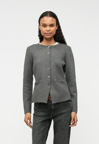 Szürke, gombos kardigán, texturált anyagból készült; kerek nyakkivágása van, elöl két zsebbel rendelkezik, és testhezálló fazonú.