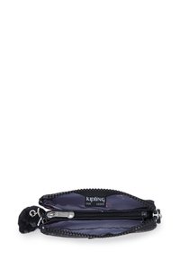 Kleine zwarte ritstas met een binnencompartiment, metalen ritser, stoffen label met de tekst "Kipling Live Light" en een bevestigd fluffy zwart sleutelhanger.