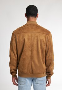 Giacca bomber in suede marrone con polsini e orlo a coste. Caratterizzata da una texture liscia e linee pulite, adatta per un abbigliamento casual.