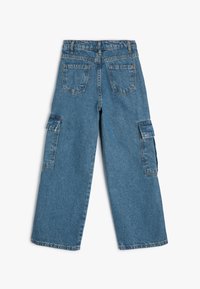 Pantalones cargo de mezclilla azul claro con un corte de pierna ancha, bolsillos cosidos y bolsillos laterales. Tejido texturizado con un acabado desgastado.