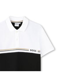 �Čiernobiely polokošeľ s golierom, ktorý má zlatý pruh zvyrazňujúci a logo "BOSS" na hrudi. Hladká bavlnená textúra.