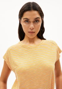 T-shirt rayé avec des bandes horizontales jaune et blanche, encolure ronde et manches courtes. Tissu en coton doux avec une coupe décontractée.