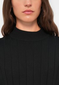 Zwarte geribbelde turtleneck trui met een hoge kraag, voorzien van verticale strepen en een textuurgebreid patroon. Glad afwerking.