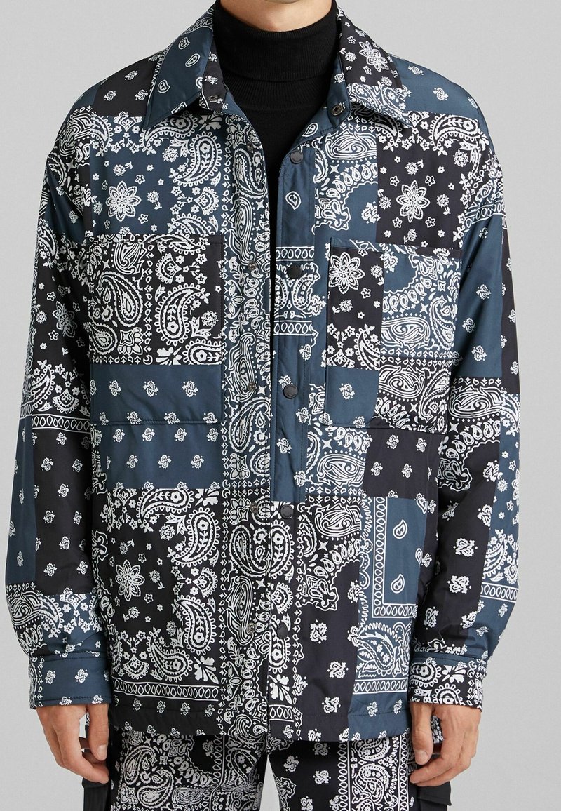 Långärmad skjorta med lappar av blå och svarta paisleymönster. Tillverkad av smidigt tyg med knäppning och två bröstfickor.