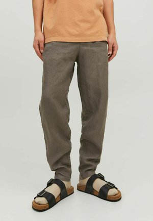 Pantaloni in lino grigio chiaro, comodi e larghi, con tasche laterali e dettagli di cucitura sottili, abbinati a sandali neri e marroni.