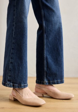 Nude slingback flade lavet af blødt ruskind, med en rund tå og en lav blokhæll, parret med mørkeblå brede ben-jeans.
