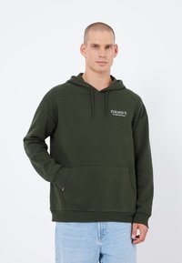 Haut à capuche vert foncé en matière douce, avec une poche avant et un cordon de serrage. Petit logo sur la poitrine gauche. Coupe décontractée.