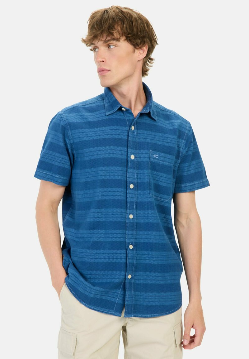 Blå kortærmet skjorte med button-down krave, der har vandrette striber og en brystlomme. Stoffet ser struktureret og letvægtsagtigt ud.