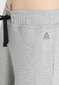 Grå bomullssweatpants med resårmidja och svart dragsko. Inkluderar en liten Reebok-logotyp på nedre sidan. Mjuk textur.