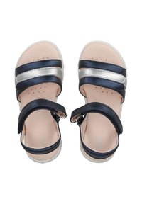 Sandalias en tonos azul marino y plateado con dos correas anchas y correas ajustables en el tobillo. Plantilla suave de color beige con perforaciones y suela de goma blanca.