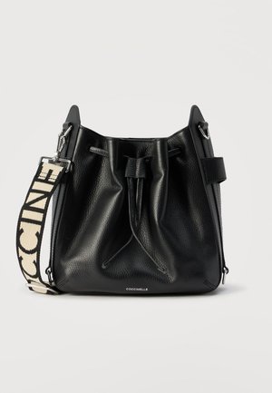 Fekete, texturált bőr vödörtáska húzózsinór záródással és levehető, széles szövet vállpánttal, melyen vastag betűs felirat található.