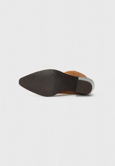 Botine din pielă întoarsă maro, cu vârf ascuțit, toc neted și talpă din cauciuc texturată cu un model geometric.