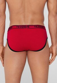 Czerwone męskie slipy wykonane z miękkiego materiału z czarnym elastycznym paskiem w talii z logo "TEZENIS". Konturowany krój z kontrastowymi wykończeniami.