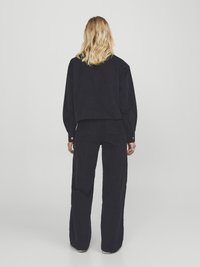 Black corduroy oversized shirt and wide-leg pants, featuring a textured surface, dropped shoulders, and buttoned cuffs.