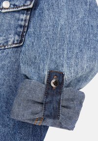 Denimhemd in hellblauer Farbe mit knöpfbarem Aufschlag und plissiertem Design, sichtbaren Nähten und glatter Textur.