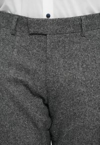 Grå skræddersyede bukser lavet af tekstureret stof, med flad front, bæltesløjfer og knaplukning i livet.