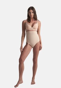 Top bikini color beige con coppe triangolari e spalline regolabili abbinato a un bottom a vita alta. Texture liscia, design senza cuciture, hardware minimale.