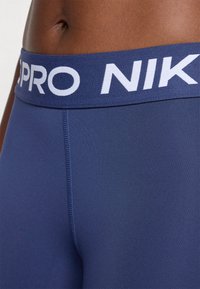 Námornícke športové legíny s bielym elastickým pásom "PRO NIKE", hladká textúra a ploché švy pre komfort a flexibilitu.