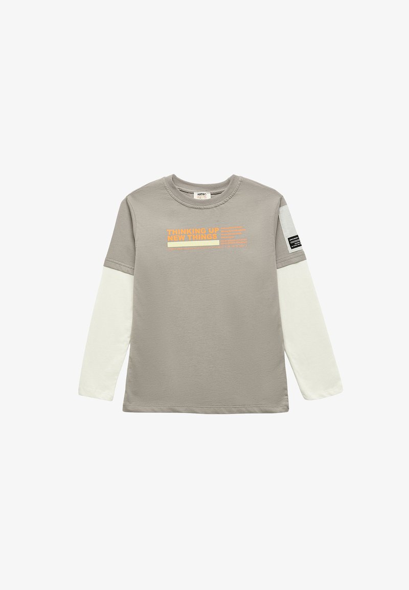Camiseta para niños de manga larga con aspecto de capas en gris y blanco, con texto naranja "THINKING UP NEW THINGS" en el frente y parche negro en la manga izquierda.