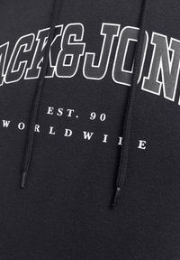 Sweat à capuche noir avec une inscription blanche audacieuse "BLACK&JON" et "EST. 90 WORLDWIDE." Cords de serrage au niveau du col ; le tissu semble texturé.