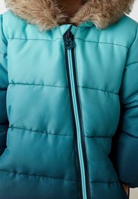 Chaqueta acolchada verde azulado con capucha forrada de piel, que presenta un cierre de cremallera y un diseño acolchado horizontal. Textura suave y cremallera de contraste.