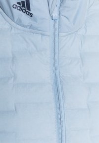 Vaaleansinen Adidas-untuvatakki, jossa on vetoketjukiinnitys, tekstuuri kangas ja embroidered-logo kaulan lähellä. Sujuvaa, kevyttä materiaalia.