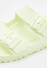 Sandale vert clair avec deux sangles ajustables, fabriquée en matériau texturé, dotée d'une semelle intérieure ergonomique et d'une épaisse semelle extérieure pour un bon soutien.