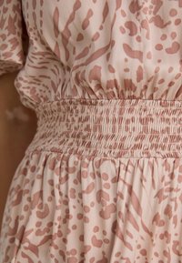 Vestido rosa empolvado con cintura fruncida, que presenta un patrón abstracto en tonos más oscuros, hecho de una tela liviana y suave.