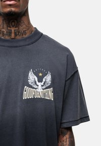 Koolgrijze oversized t-shirt met een ronde halslijn, voorzien van een witte grafiek van vleugels en de tekst "GOODFORNOTHING" op de voorkant.